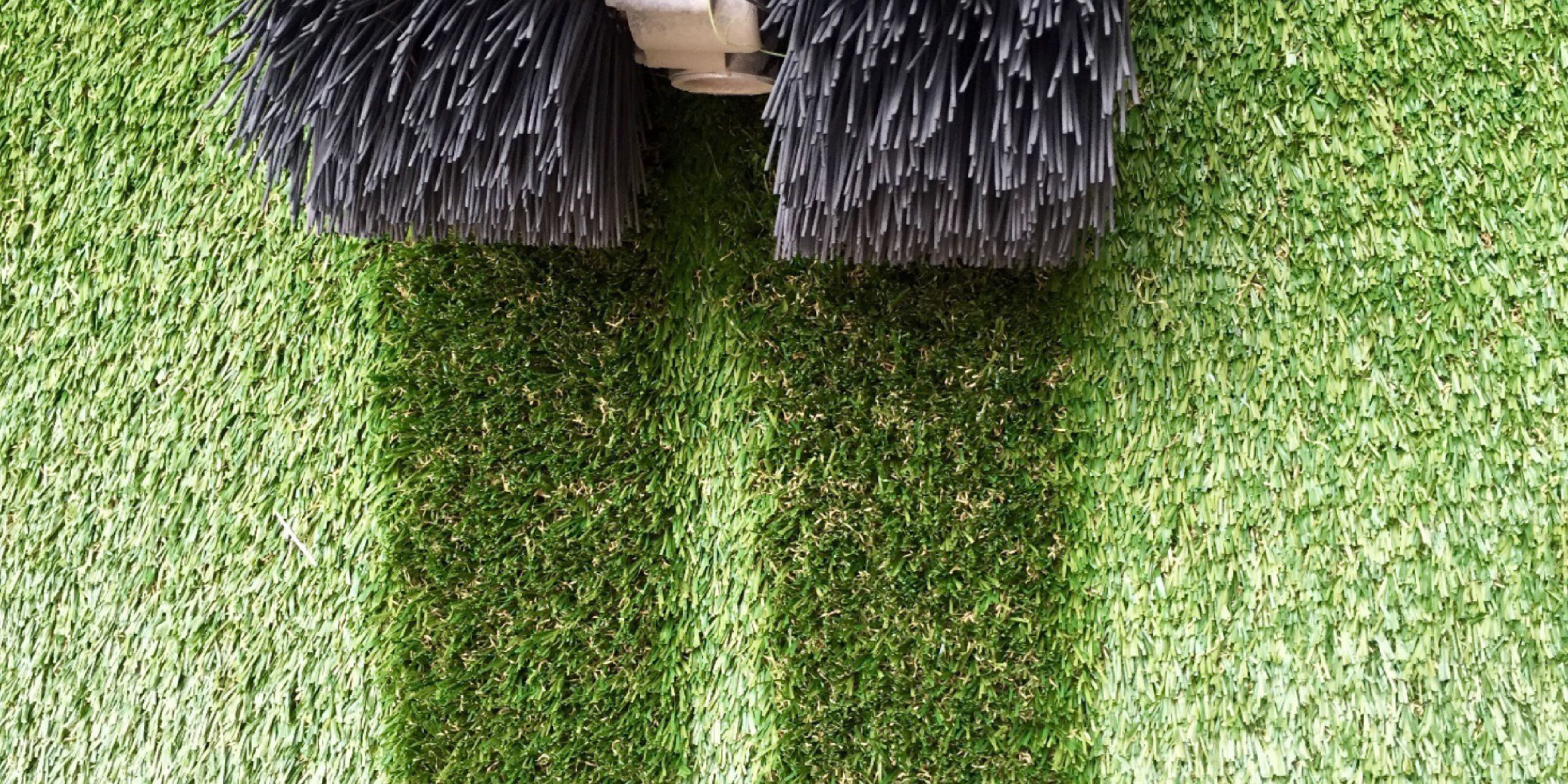 Close-up of a power broom used on artificial grass for maintenance.